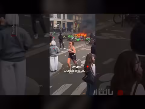 امرأة تركض أمام حاجز محترق وسط احتجاجات باريس