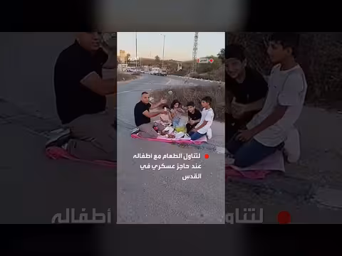 مواطن فلسطيني يتناول الطعام مع أطفاله عند حاجز عسكري في القدس